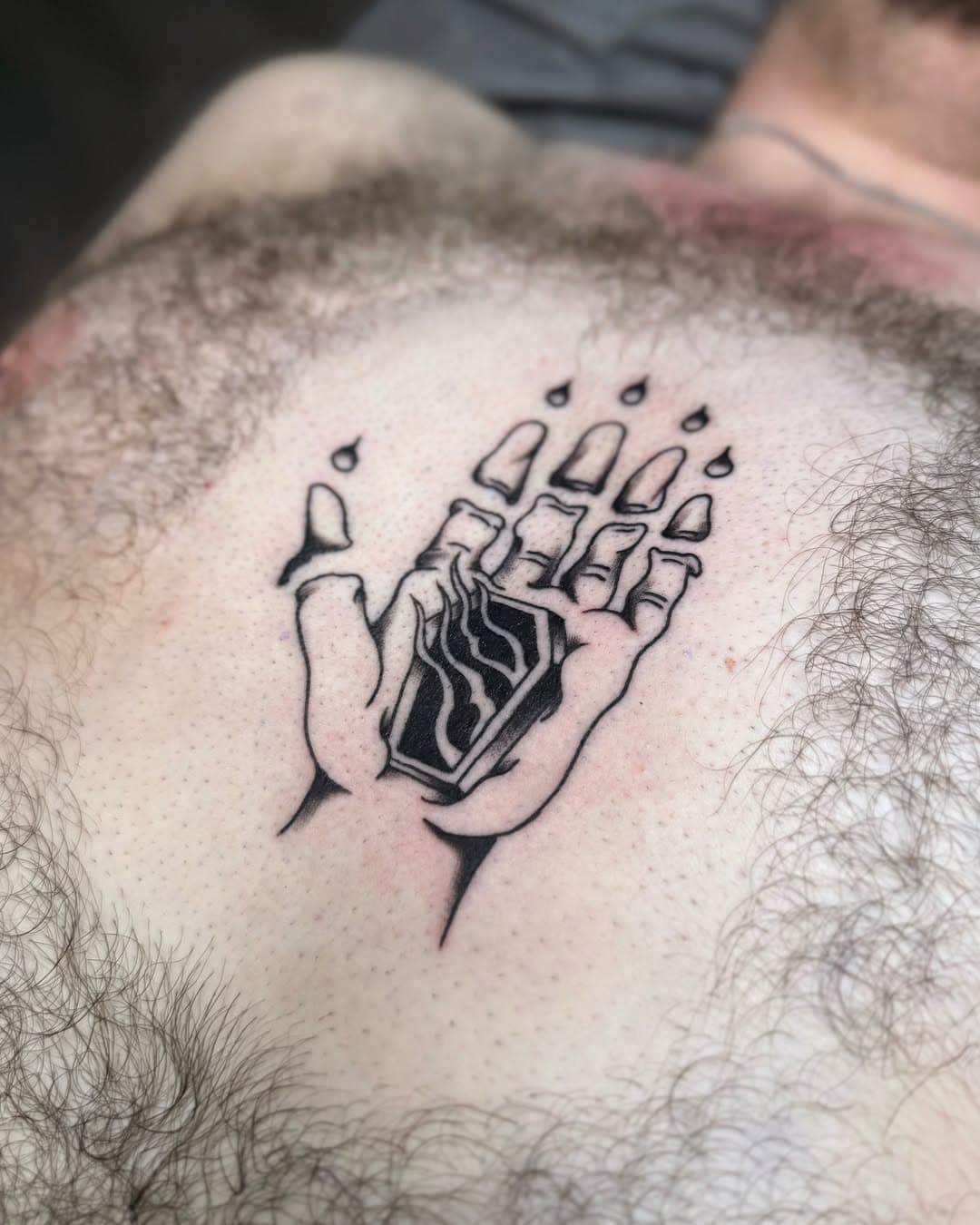 Tattoo of dismembered hand with a coffin as the palm.