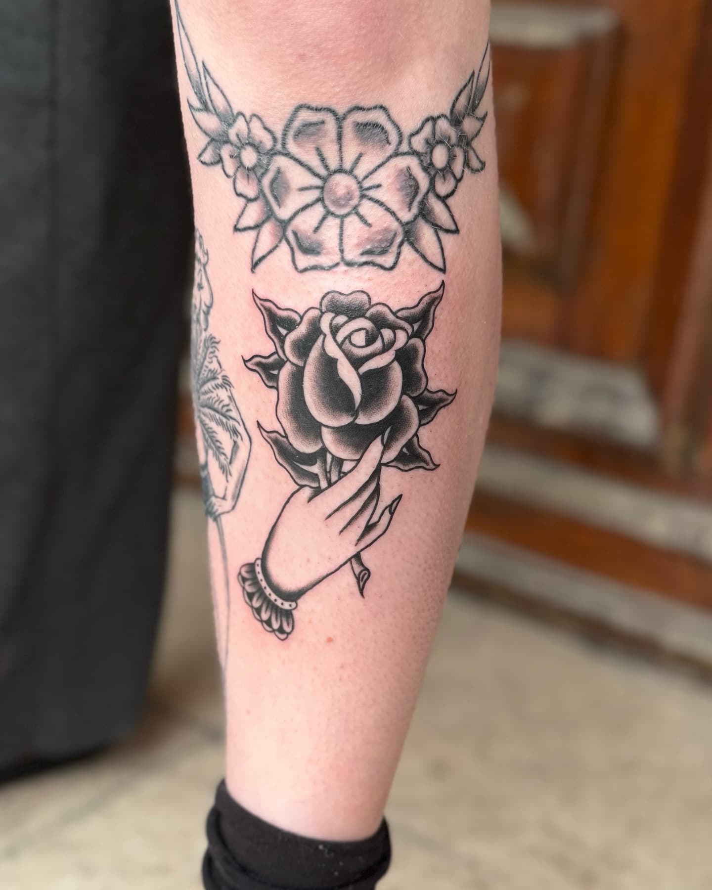 Traditional tattoo of a hand holding a black rose.