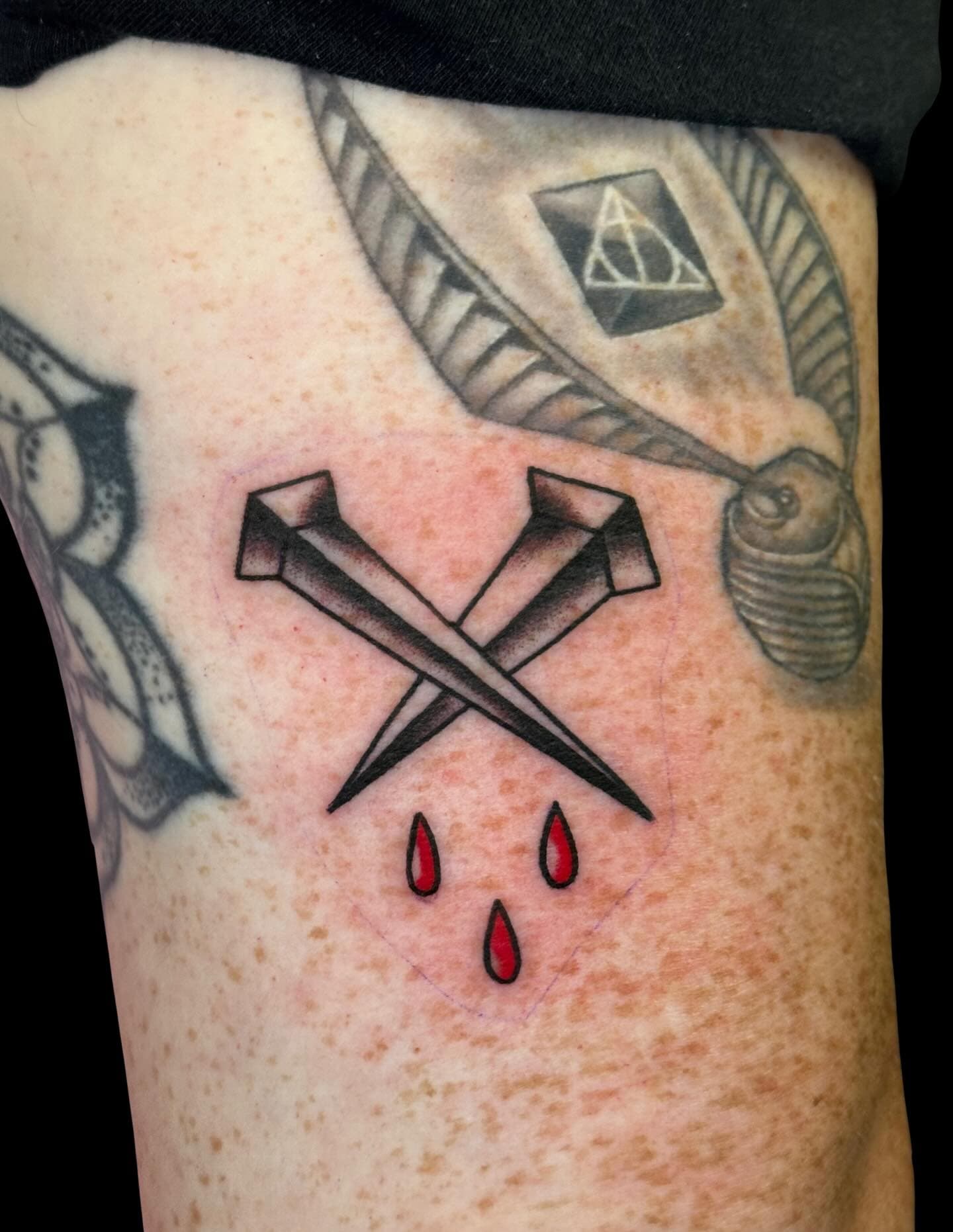 Tattoo of two crossed nails with drips of blood